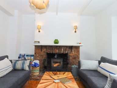 A living room with a fireplace and sofas at Captains Cottage in Brixham
