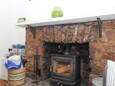 A living room with a stone fireplace and wood stove at Captains Cottage Brixham
