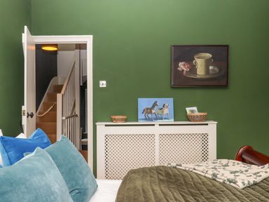 A bedroom with a green wall and a staircase at Captains Cottage in Brixham