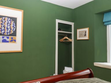 A bedroom with a closet and artwork on walls at Captains Cottage in Brixham