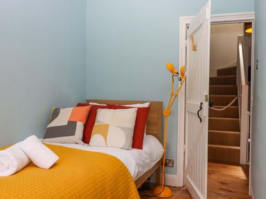A bedroom with a bed and a staircase at Captains Cottage Brixham