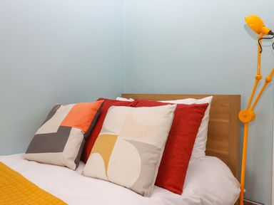 A bedroom with a bed and colorful pillows at Captains Cottage in Brixham