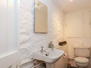 A bathroom with a sink, toilet, and mirror at Captains Cottage Brixham