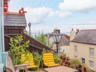 An outdoor seating area with yellow chairs and a table at Captains Cottage in Brixham