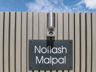 A sign with the name Noflash Malpal against a wooden wall in Bishop Sutton