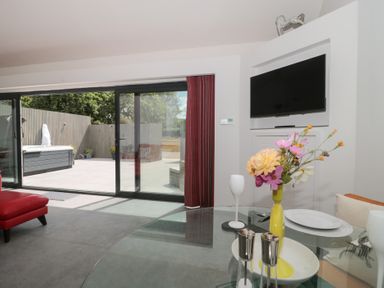 A living room with a glass table and red chair at Noflash Malpal in Bishop Sutton
