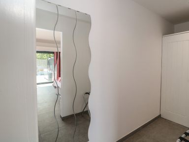 A hallway with a mirror and a view of a bedroom at Noflash Malpal in Bishop Sutton