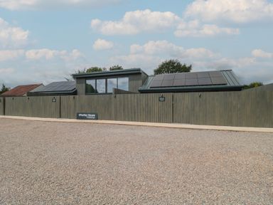 A house with solar panels and a fence at Whatley House Holidays in Bishop Sutton