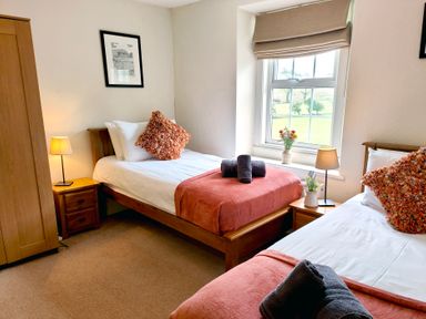 A bedroom with two beds and a window at Bush Nook House Brampton