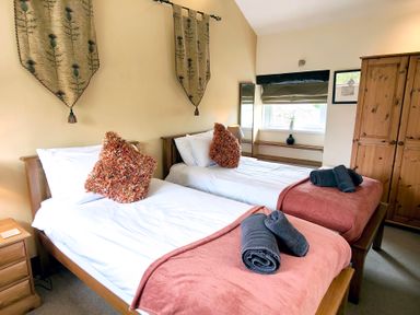 A bedroom with twin beds and wooden furniture at Bush Nook House in Brampton