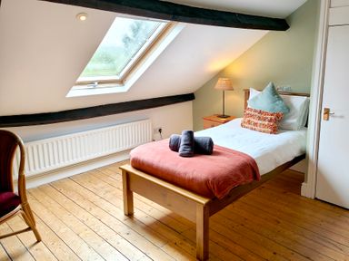 A bedroom with a bed, lamp, chair, and window at Bush Nook House in Brampton