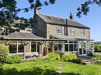 A house with a conservatory and garden at Bush Nook House in Brampton, Cumbria