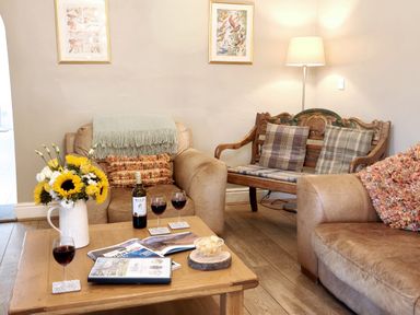 A living room with a coffee table and wine at Bush Nook House in Brampton, Cumbria