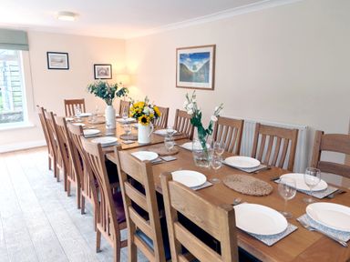 A dining room with a long table set at Bush Nook House in Brampton, Cumbria