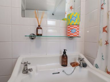 A sink and mirror with soap and decorative items at Moot Cottage in Driffield