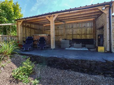 An outdoor seating area with garden furniture and a canopy at Thelma’s Lodge near Pontyates
