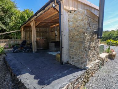 An outdoor space with a hot tub and chairs at Thelma’s Lodge near Pontyates