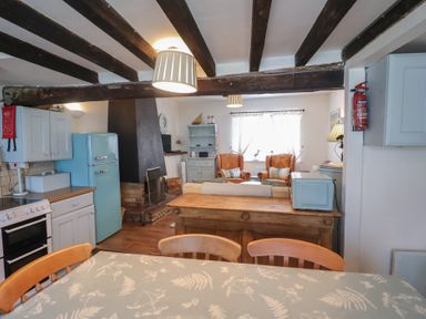 A kitchen with a blue refrigerator and dining table at Buttercup in Blakeney, Norfolk