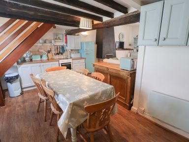 A kitchen with a dining table and cooking appliances at Buttercup in Blakeney, Norfolk