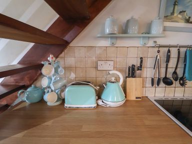 A kitchen with a kettle, toaster, and cups on the counter at Buttercup in Blakeney, Norfolk