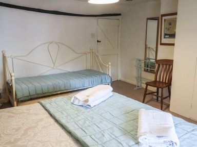 A bedroom with two beds and a chair at Buttercup in Blakeney, Norfolk