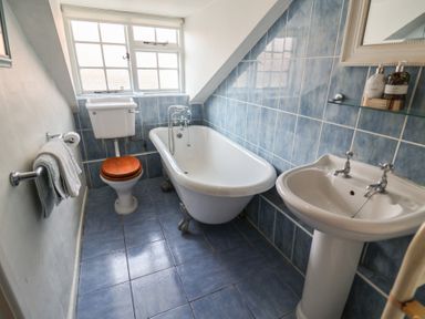 A bathroom with a bathtub, toilet and sink at Buttercup in Blakeney, Norfolk