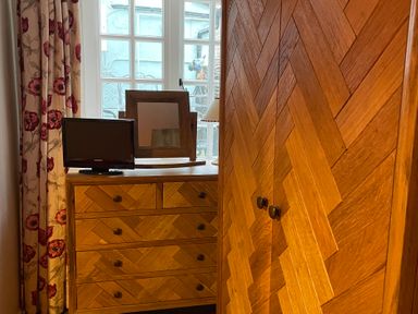 A bedroom with a wardrobe, dresser, television, and mirror at The Bittern in Blakeney, Norfolk