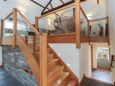 An entrance hall with staircase and glass railing at The Barn at Sunny Barn in Brecon