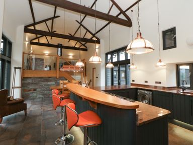 A kitchen with a bar and stools at The Barn at Sunny Barn in Brecon