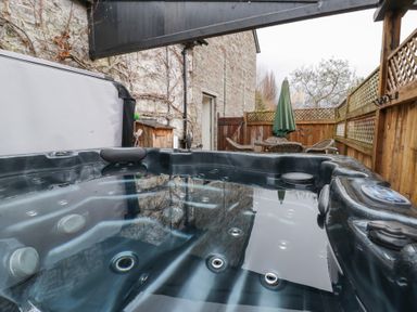 An outdoor area with a hot tub and patio furniture at The Barn at Sunny Barn, Brecon