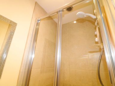 A shower enclosure with glass doors and shower head at Sunnyside Lodge in Thorpe-On-The-Hill