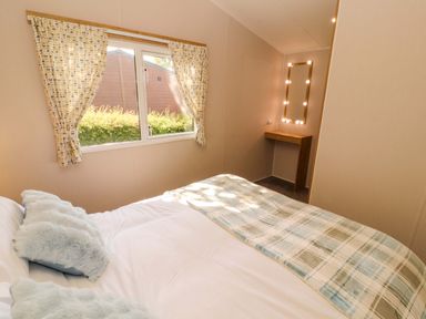 A bedroom with a bed, vanity table and window at Barneys Retreat in Carnforth