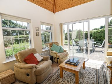 A conservatory with seating area and sliding doors leading to patio at Knockroe Lodge