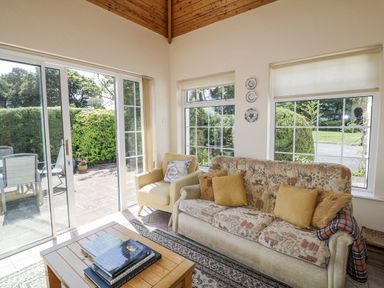 A conservatory with a sofa and armchair at Knockroe Lodge