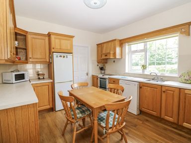 A kitchen with wooden cabinets and appliances at Knockroe Lodge