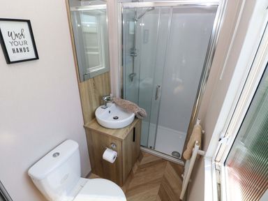 A bathroom with a shower, toilet, and wash basin at No 13 Broadfield Farm Holiday Park in Saundersfoot