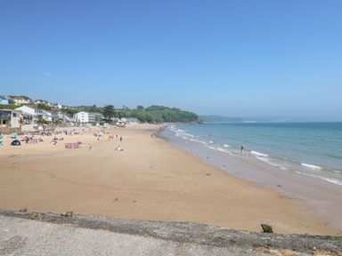 A beach with people and houses at No 13 Broadfield Farm Holiday Park in Saundersfoot