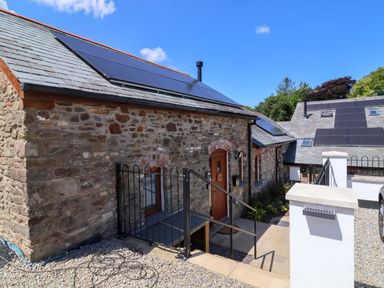 An outdoor view of a cottage with solar panels at Hedgehog Highway in Parkham