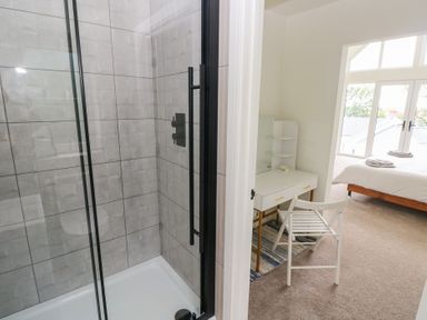 A bathroom with a shower and chair at Ty Landsker in Milford Haven