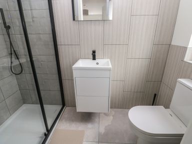 A bathroom with a shower, wash basin, and toilet at Ty Landsker in Milford Haven