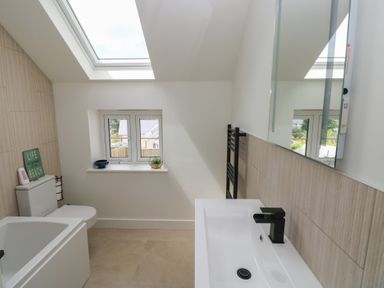 A bathroom with a bathtub, sink, and toilet at Ty Landsker in Milford Haven