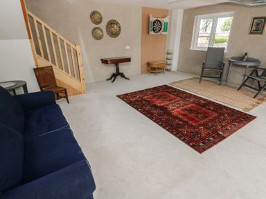 A snug with a sofa, rug, table, and dartboard at Ty Landsker in Milford Haven