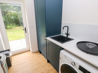 A laundry room with a washing machine and sink at Ty Landsker in Houghton near Neyland