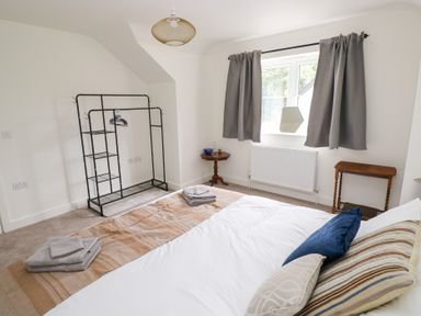 A bedroom with a bed and a clothes rack at Ty Landsker in Houghton near Neyland