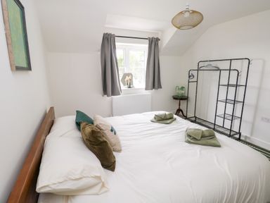 A bedroom with a bed and a clothes rack at Ty Landsker in Houghton near Neyland