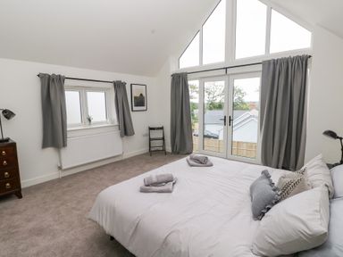 A bedroom with a bed and windows at Ty Landsker in Houghton near Neyland