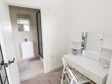 A bathroom with a vanity table and door at Ty Landsker in Houghton near Neyland