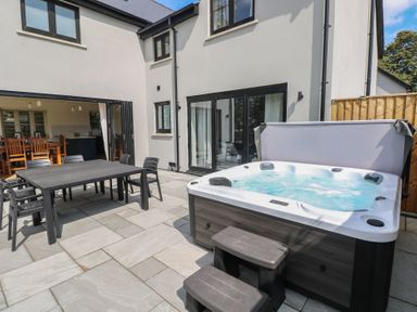 A garden with a hot tub and outdoor dining setup at Ty Landsker in Houghton near Neyland