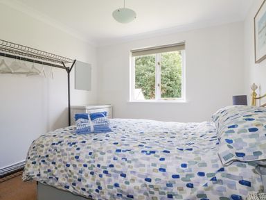 A bedroom with a bed, mirror, and window at Acorns in Falmouth