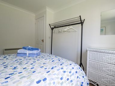 A bedroom with towels on the bed and a rack in the corner at Acorns in Falmouth